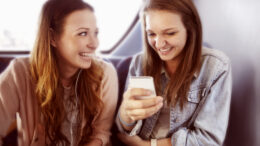 Two young women looking at a phone on the bus