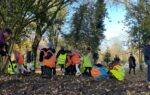 primary school children in high-vis vests plant bulbs in a sunny park