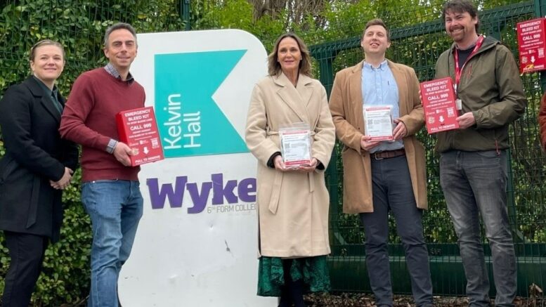 representatives from the council and its partners stand at the entrance to Wyke College, holding examples of the bleed kit boxes and contents