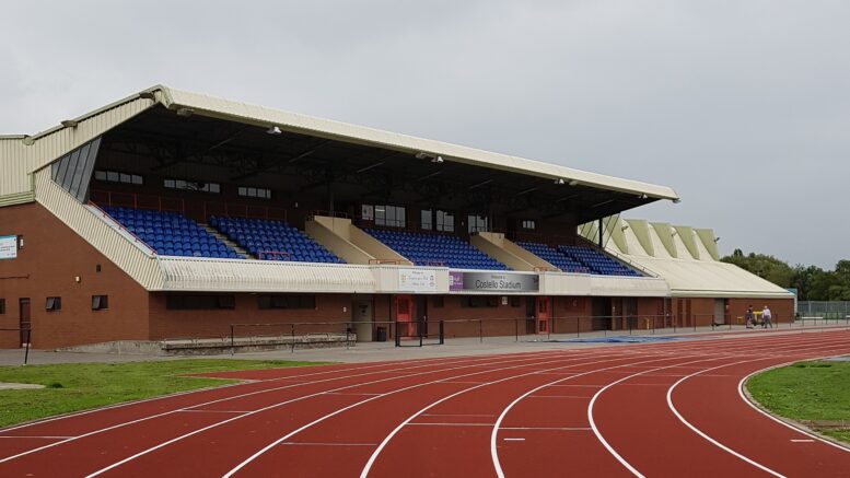 A close up of Costello Stadium running track with the stand in the background.