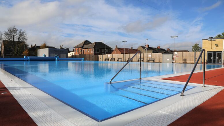 An outdoor pool shining in the sunshine with blue skies