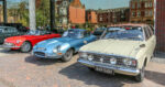 3 classic cars in a line - red, blue and cream coloured.