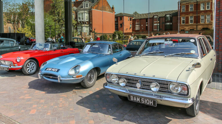 3 classic cars in a line - red, blue and cream coloured.