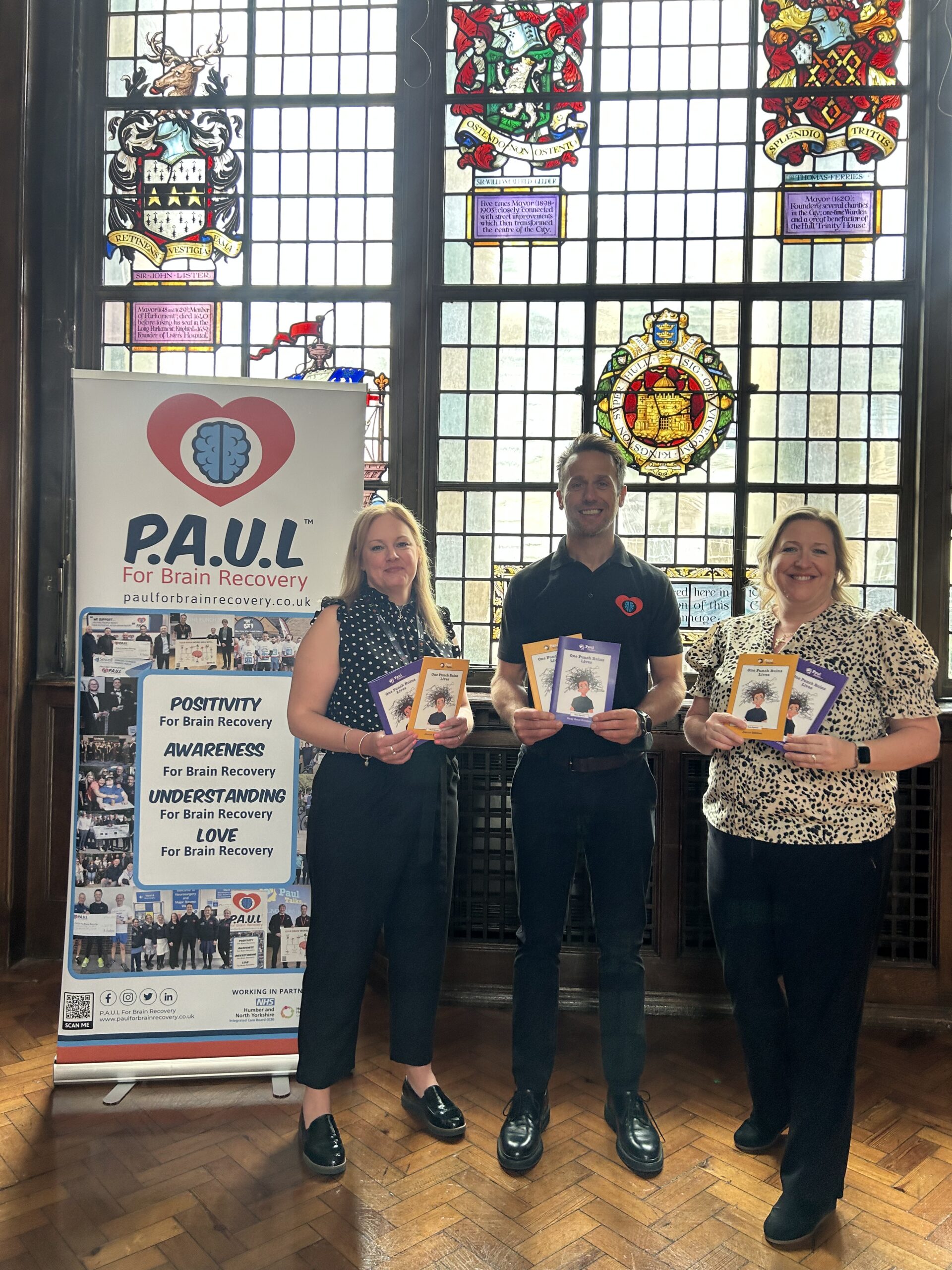 Paul is stood holding leaflets and smiling.