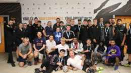 People smiling wearing medals as they pose in a group photo.