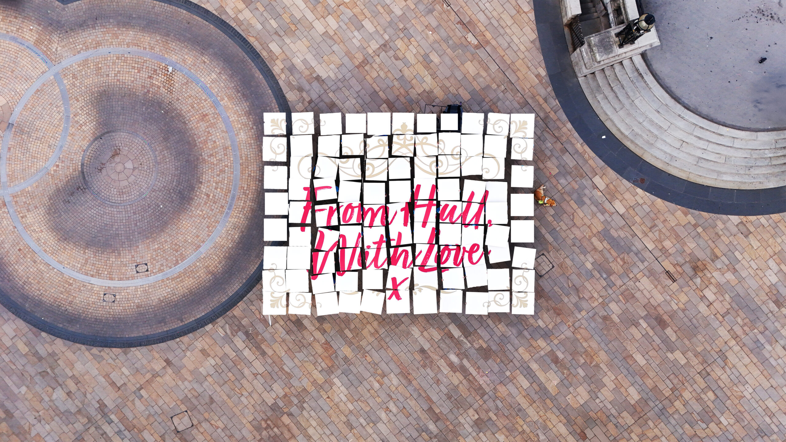 An image taken from above of pieces of people holding up pieces of white card to show an envelope with From Hull with love written in red across the front