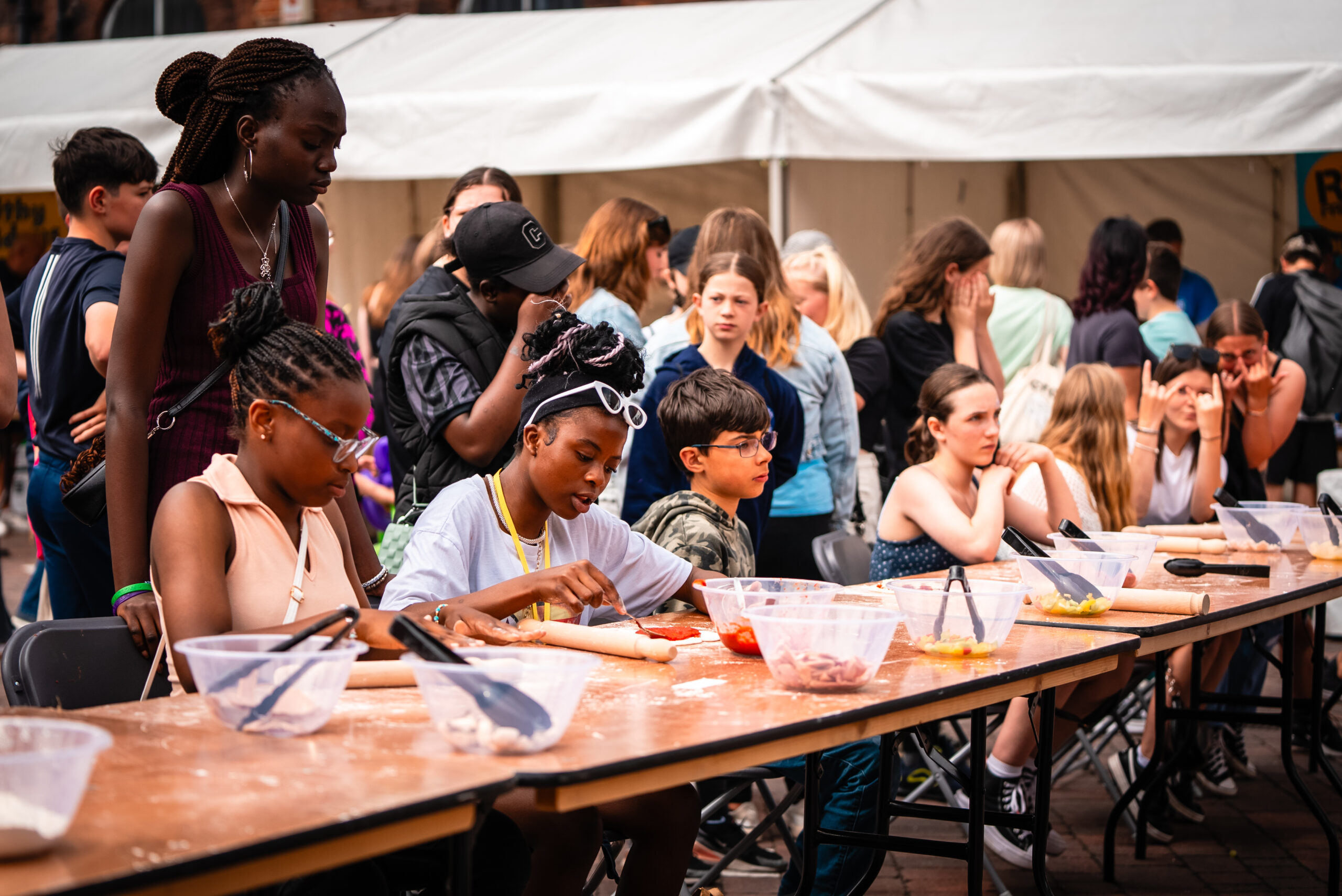 In an image taken at last year's event, children and young people sit at a trestle table doing a craft activity. The background is bustling with more people