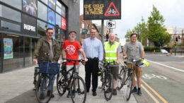 Councillor Mark Ieronimo, cabinet portfolio holder for transport and infrastructure at Hull City Council, with members of Hull’s Cycle Forum in front of a VMS sign displaying a message from the 'Share the Road' campaign.