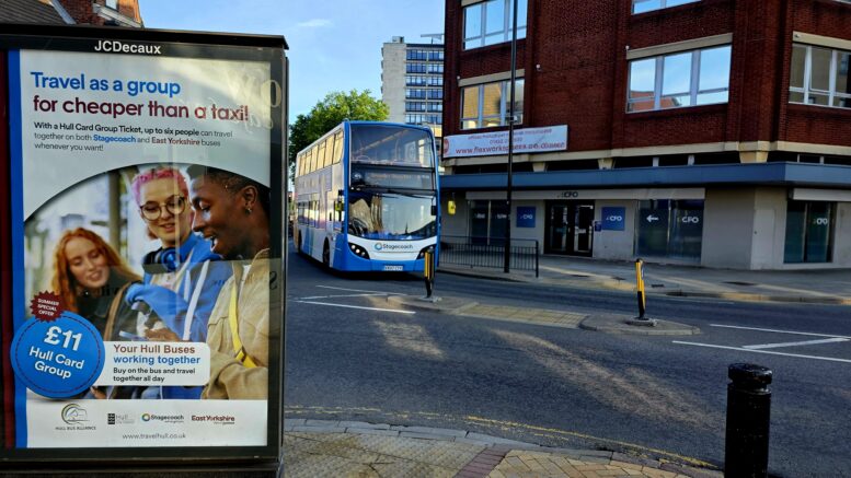 A Stagecoach bus driving around Hull City Centre with a display board highlighting the summer group travel offer.