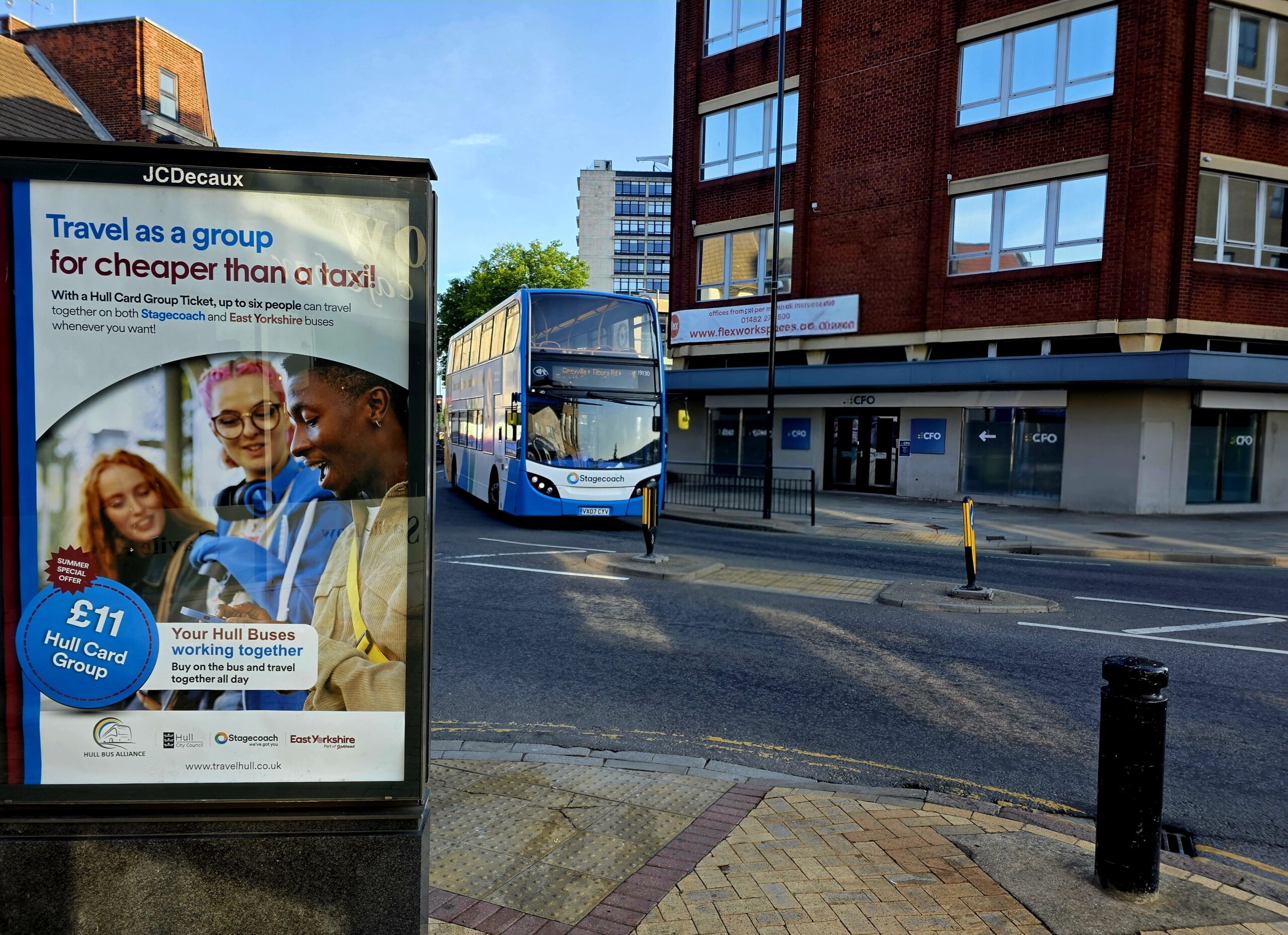 A Stagecoach bus driving around Hull City Centre with a display board highlighting the summer group travel offer.