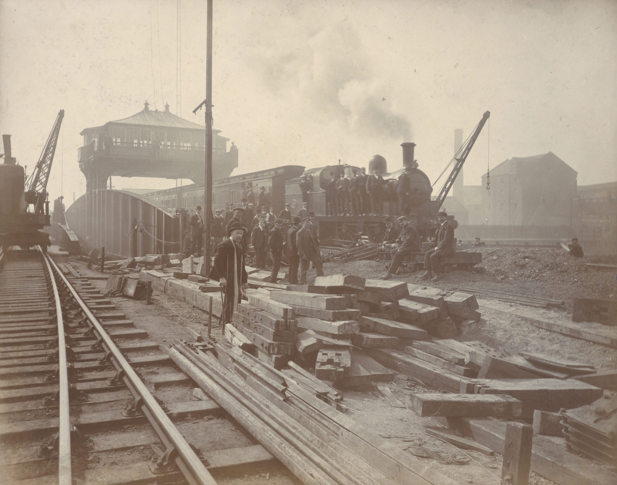 A black and white photograph of a railway with workers and a train