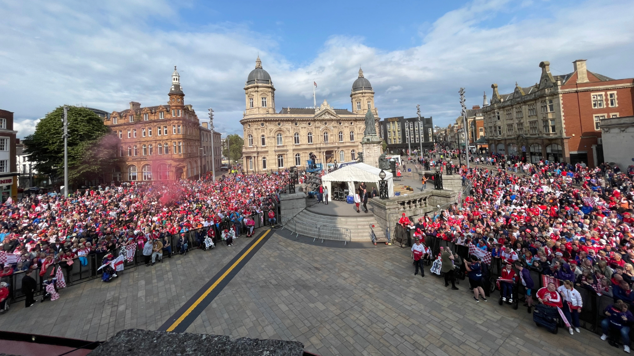 An elevated shot of thousands of people in an open square with historic buildings in the background