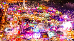 An aerial view of a fairground at night with thousands of bright lights
