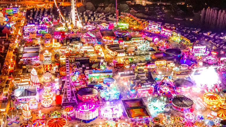 An aerial view of a fairground at night with thousands of bright lights