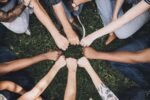 an image of a number of people making a fist and placing their hands together to form a circle. Only their arms and hands can be seen