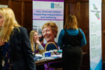 A woman sits listening to someone at an adult social care event