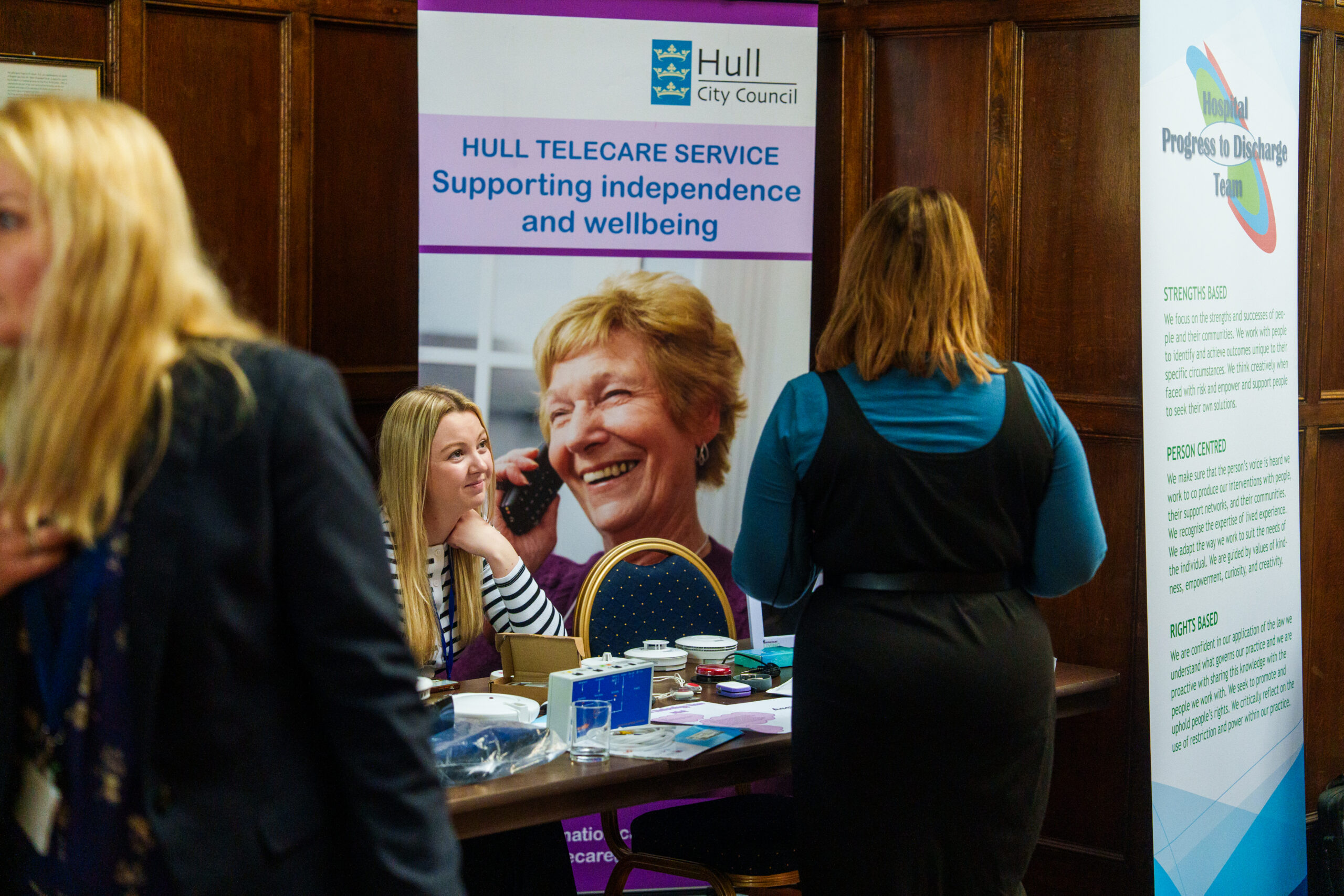 A woman sits listening to someone at an adult social care event