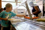 A boy adds food to his school meal in a canteen.