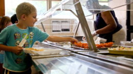 A boy adds food to his school meal in a canteen.
