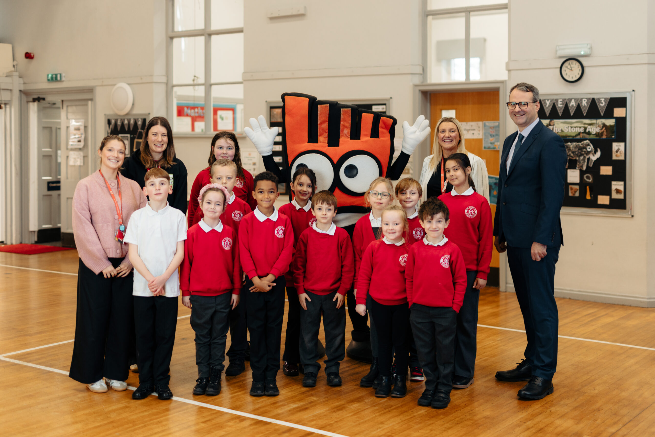 Staff and children at St Nicholas Primary School welcome Living Streets mascot, Strider, during their launch assembly for the Living Streets WOW Challenge