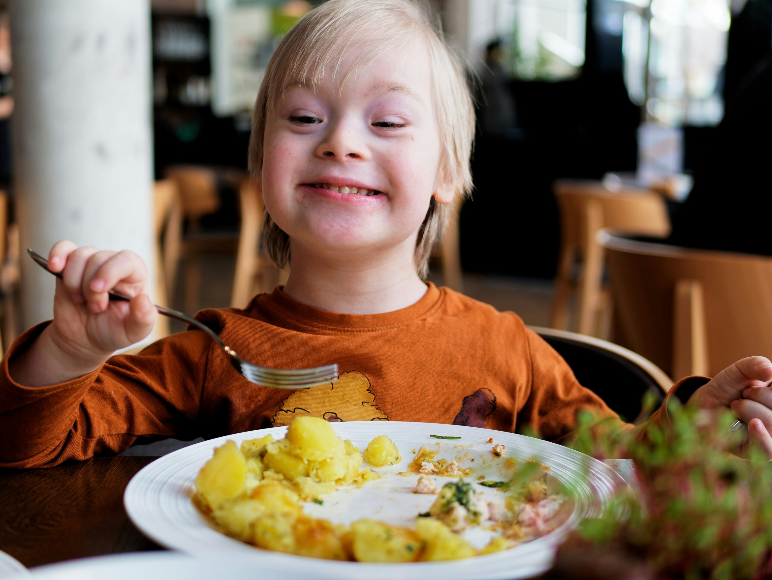 A boy with Down's syndrome smiles as he eats a meal