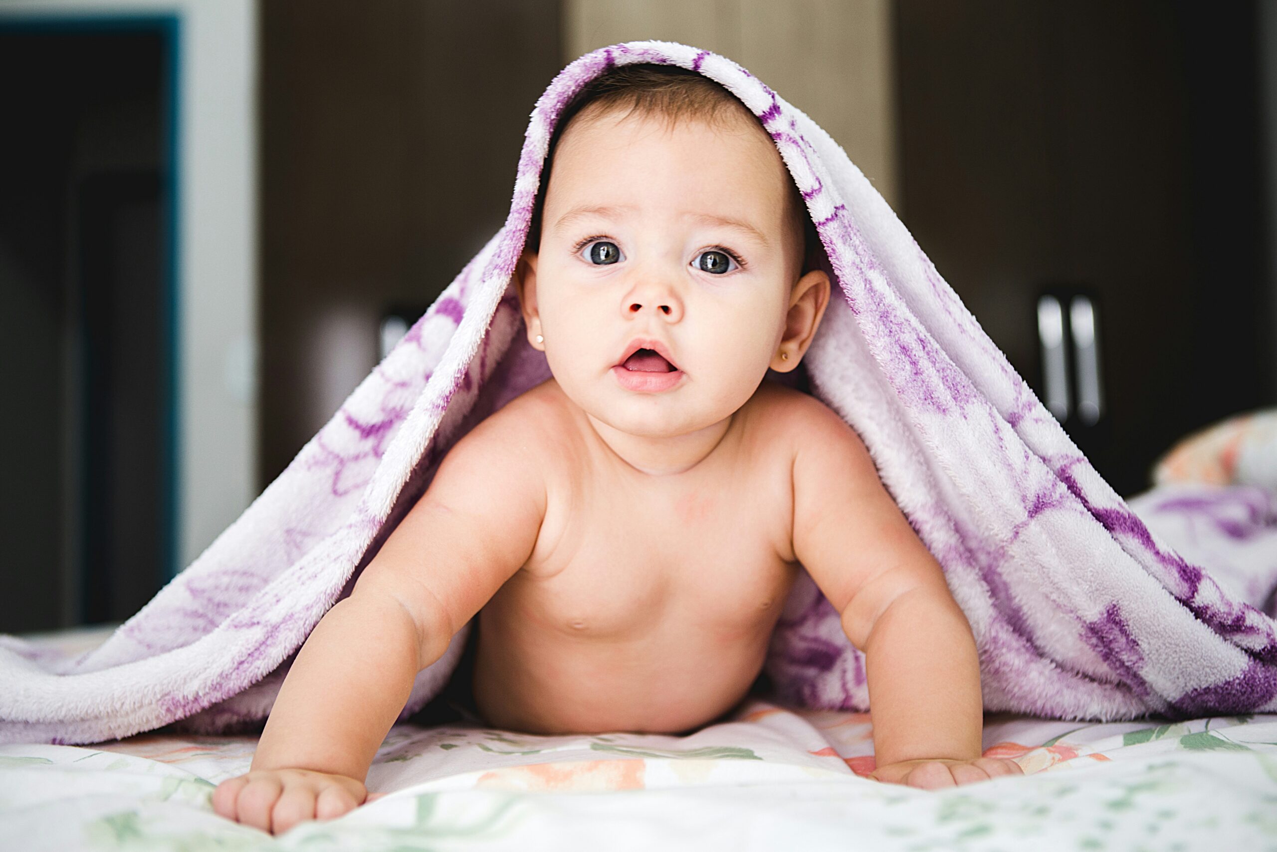 Baby looking up under purple towel