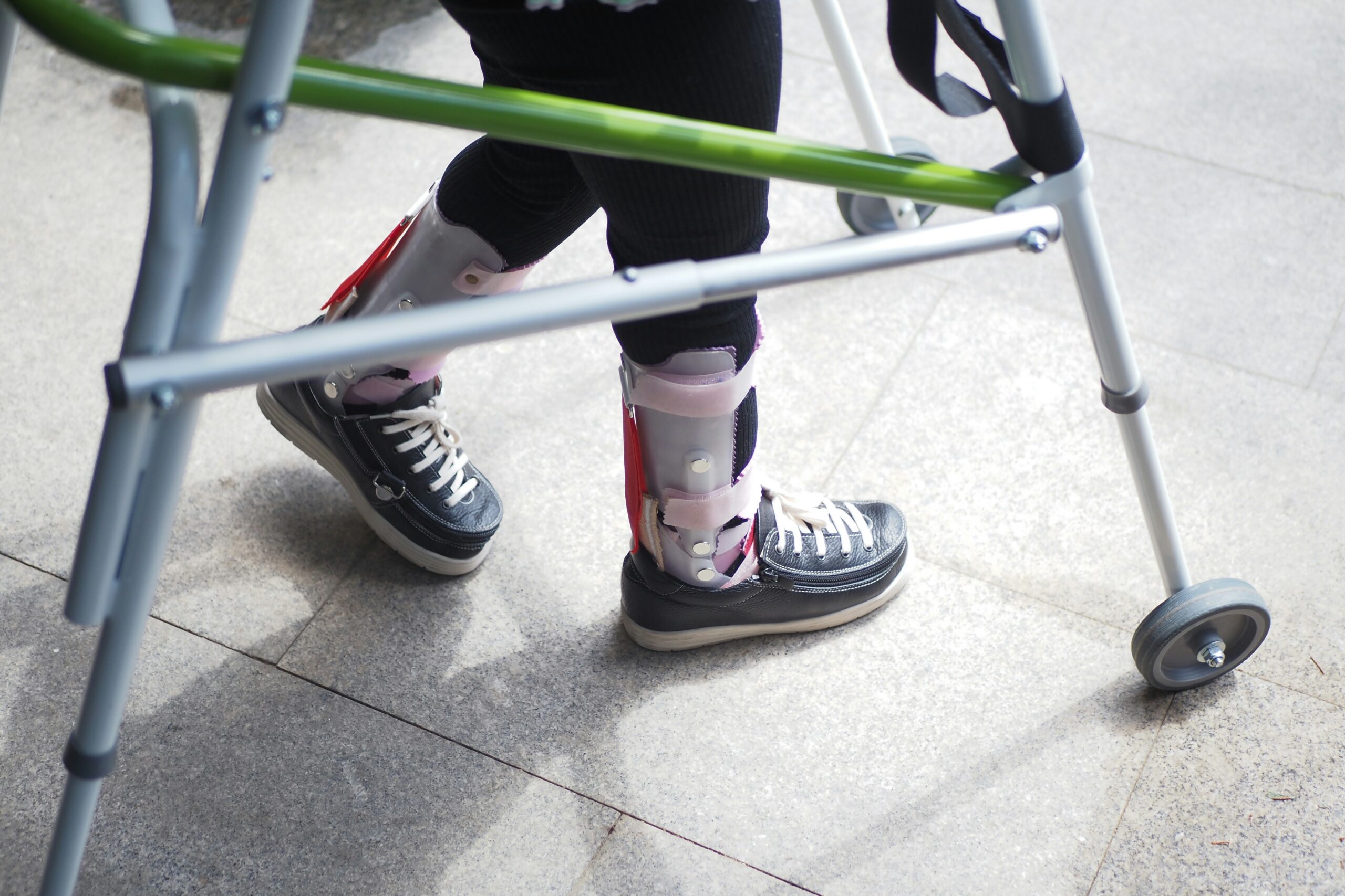 child with walking frame and knee orthosis outdoor