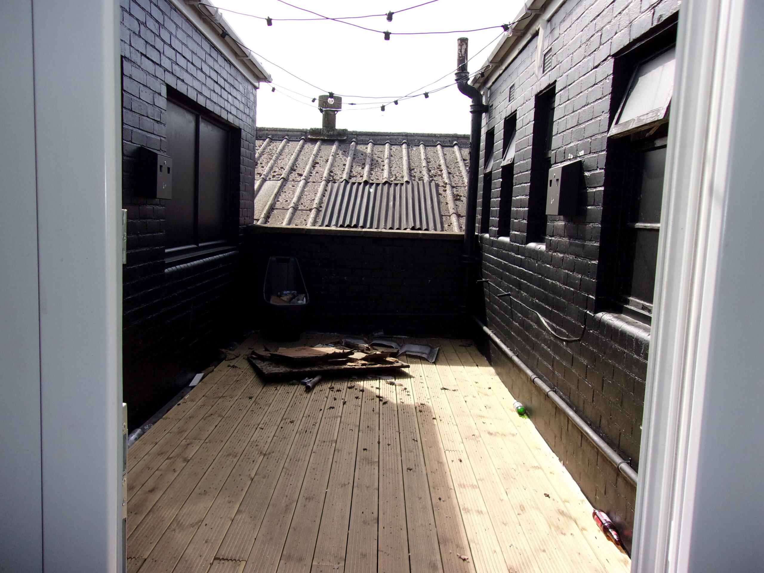 A photo of the smoking area, which has a low wall at the far end, and is open air