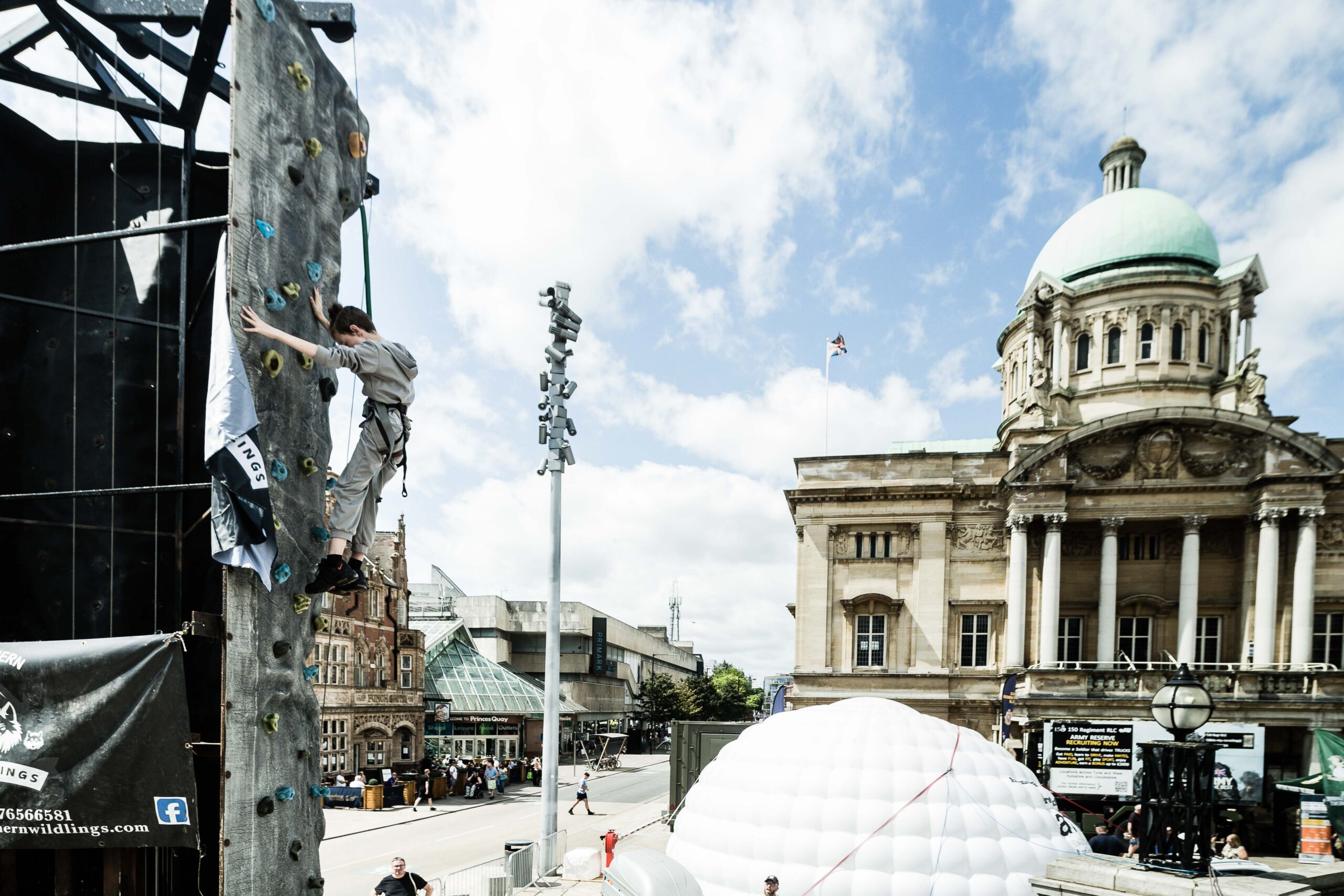 An elevated shot of a civic building in the background and a climbing wall with young person climbing in the foreground