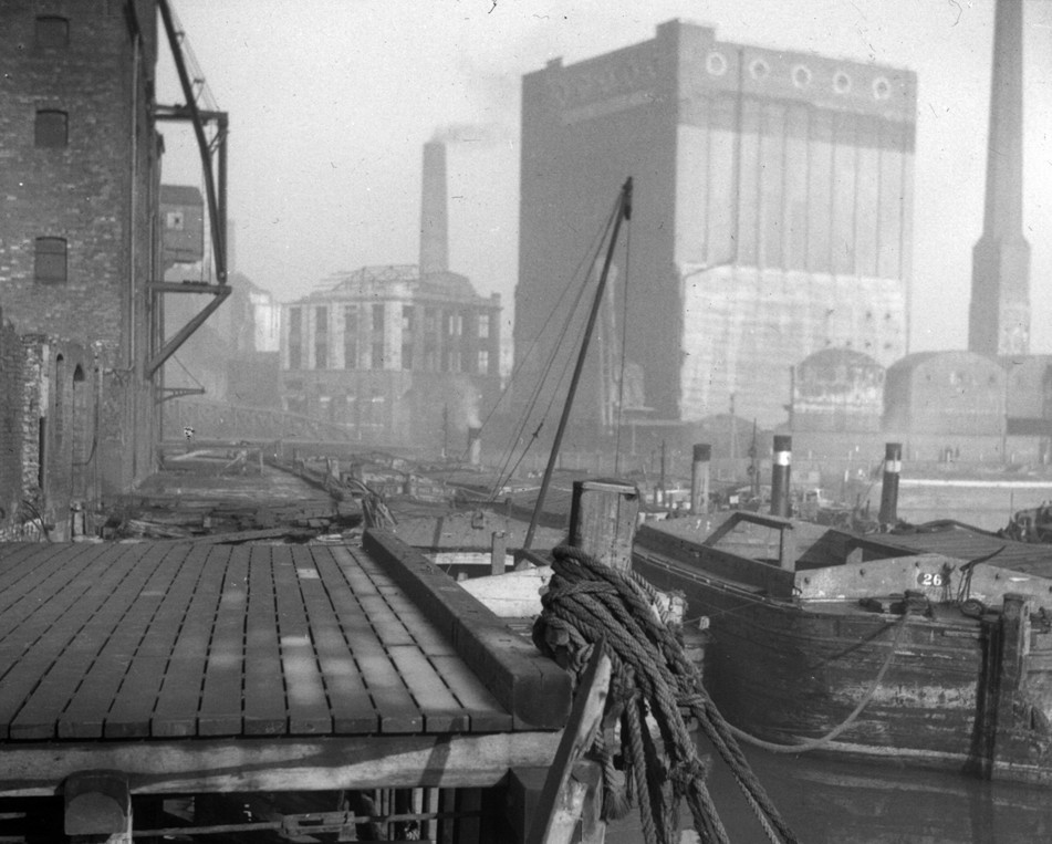 black and white image of a dock with tall buildings in background