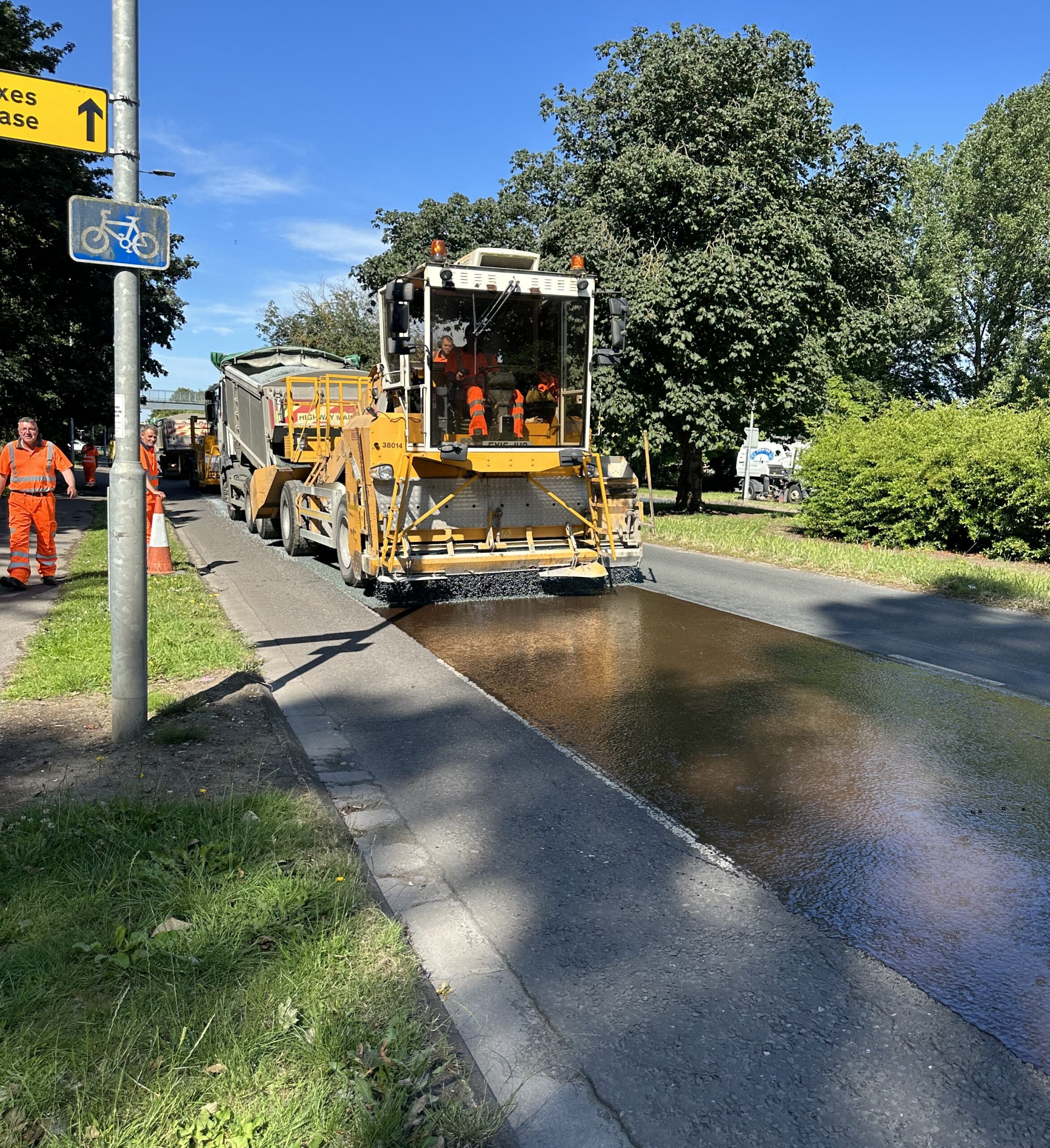 Council staff and machinery undertaking surface dressing of a road