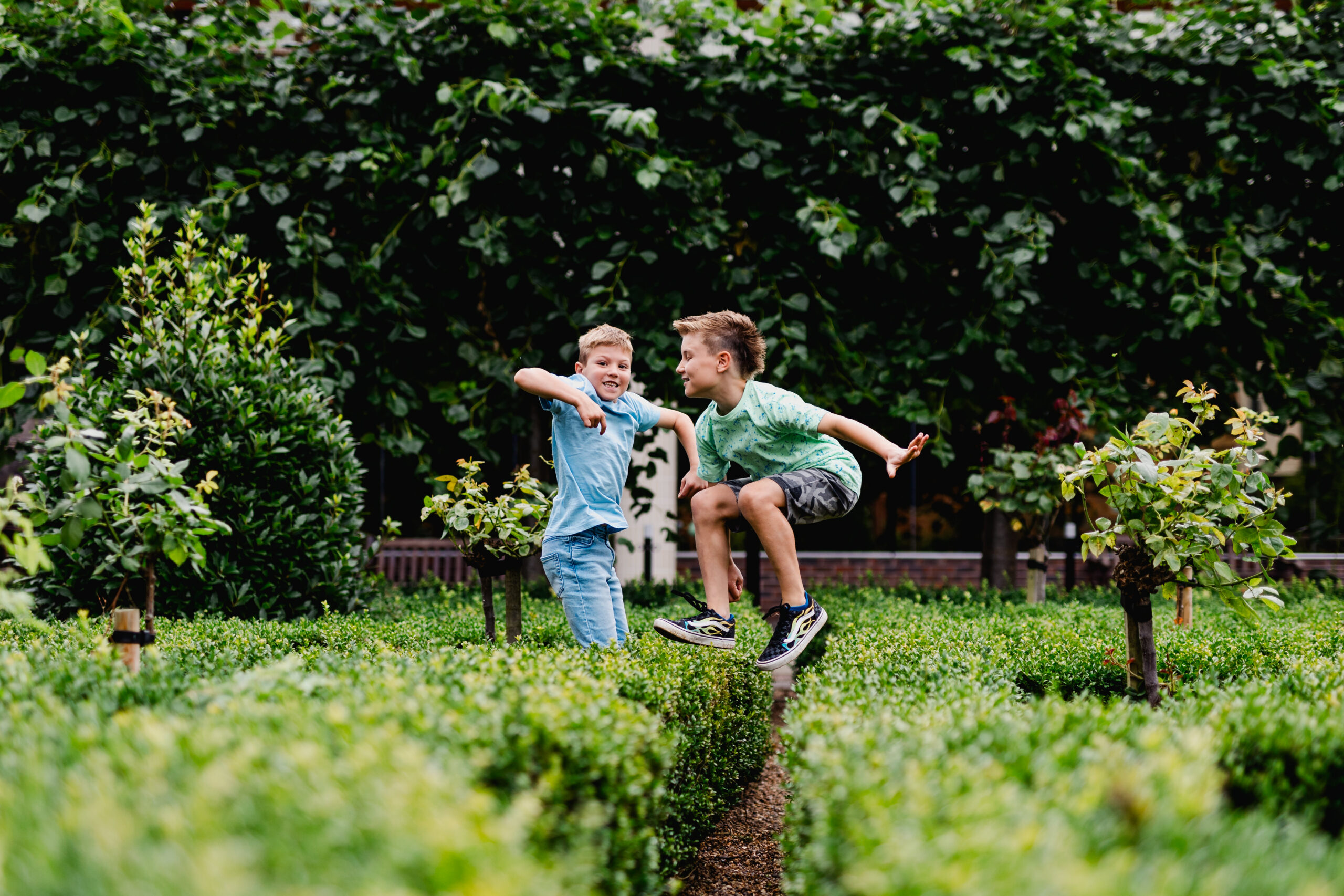 two young boys leap into the air in a large grassy area