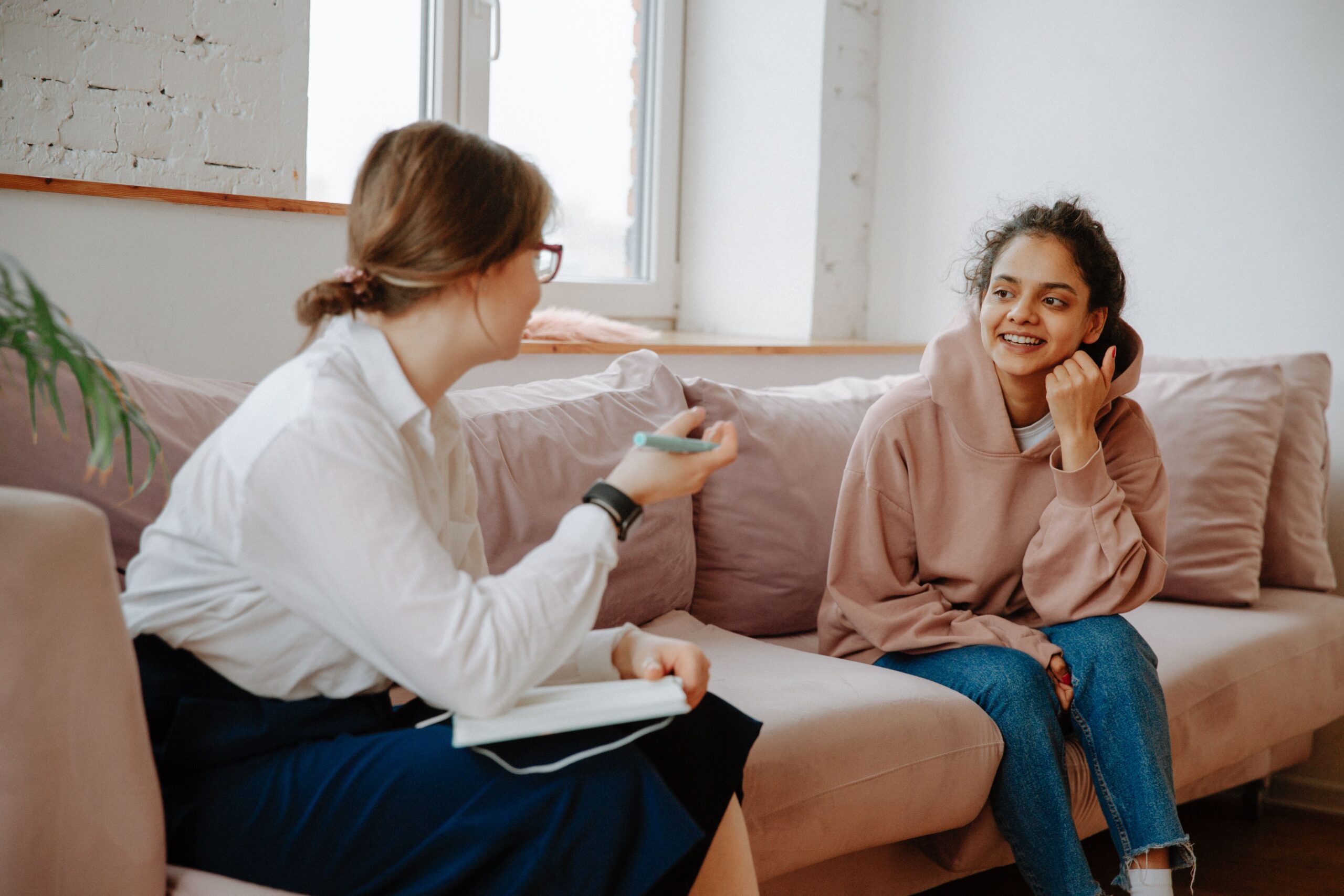 A teenager sat on a sofa talking to a female adult